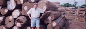 Photo of a man standing in front of many chopped trees